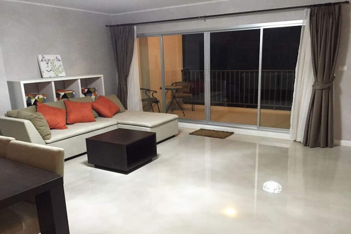 A modern living room with a sofa, coffee table, and a sliding glass door leading to a balcony.