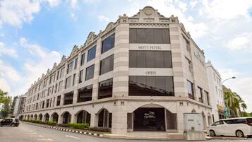 A large, historic building with the sign "MOTY HOTEL OPEN" on the front. It features a grand entrance with a large archway and multiple windows.