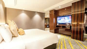 Une chambre d’hôtel avec un grand lit, un téléviseur à écran plat fixé sur un panneau en bois et une moquette à rayures jaunes.