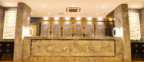 Un área de recepción con mostradores de mármol, un conducto de ventilación central y suelo de mármol.