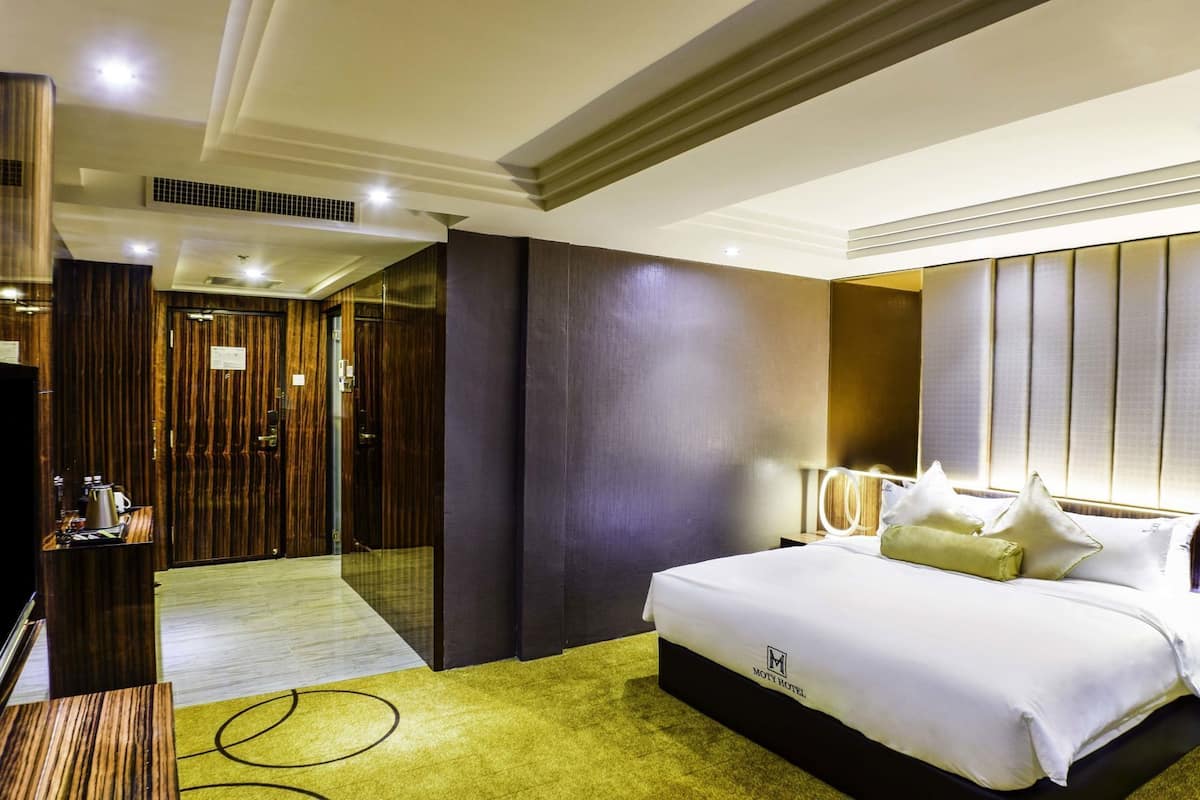 Une chambre d’hôtel avec un lit, une table de chevet, une lampe et une vue sur le couloir.