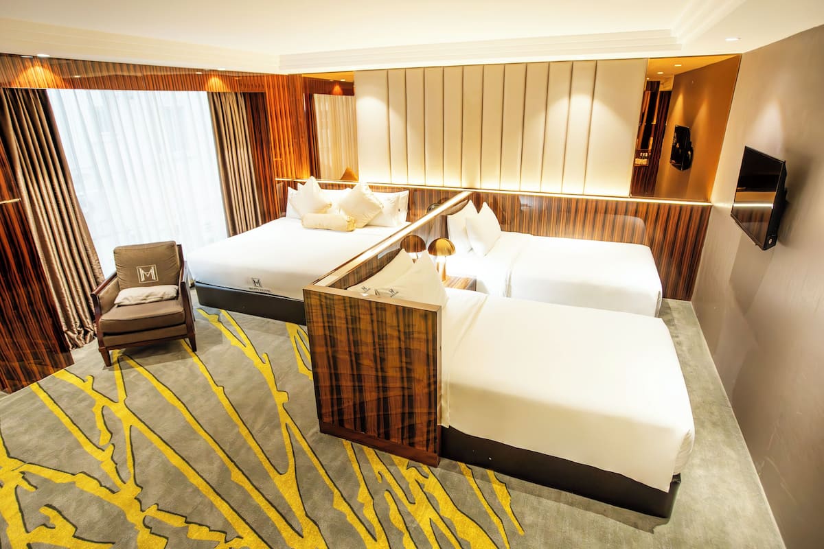 Une chambre d’hôtel avec un grand lit, un lit plus petit, une chaise et un miroir.