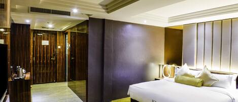 A hotel room with a large bed, a desk with a lamp, and a mirror.