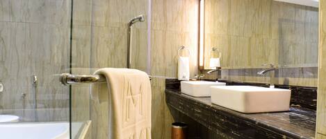A modern bathroom with a glass-enclosed shower, a white bathtub, and a marble countertop with a sink and mirror.