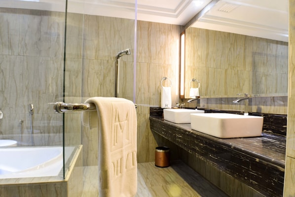 A modern bathroom with a glass-enclosed shower, a white bathtub, and a marble countertop with a sink and mirror.