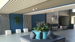 Un vestíbulo moderno con un sofá modular, pufs blancos y una planta en maceta.