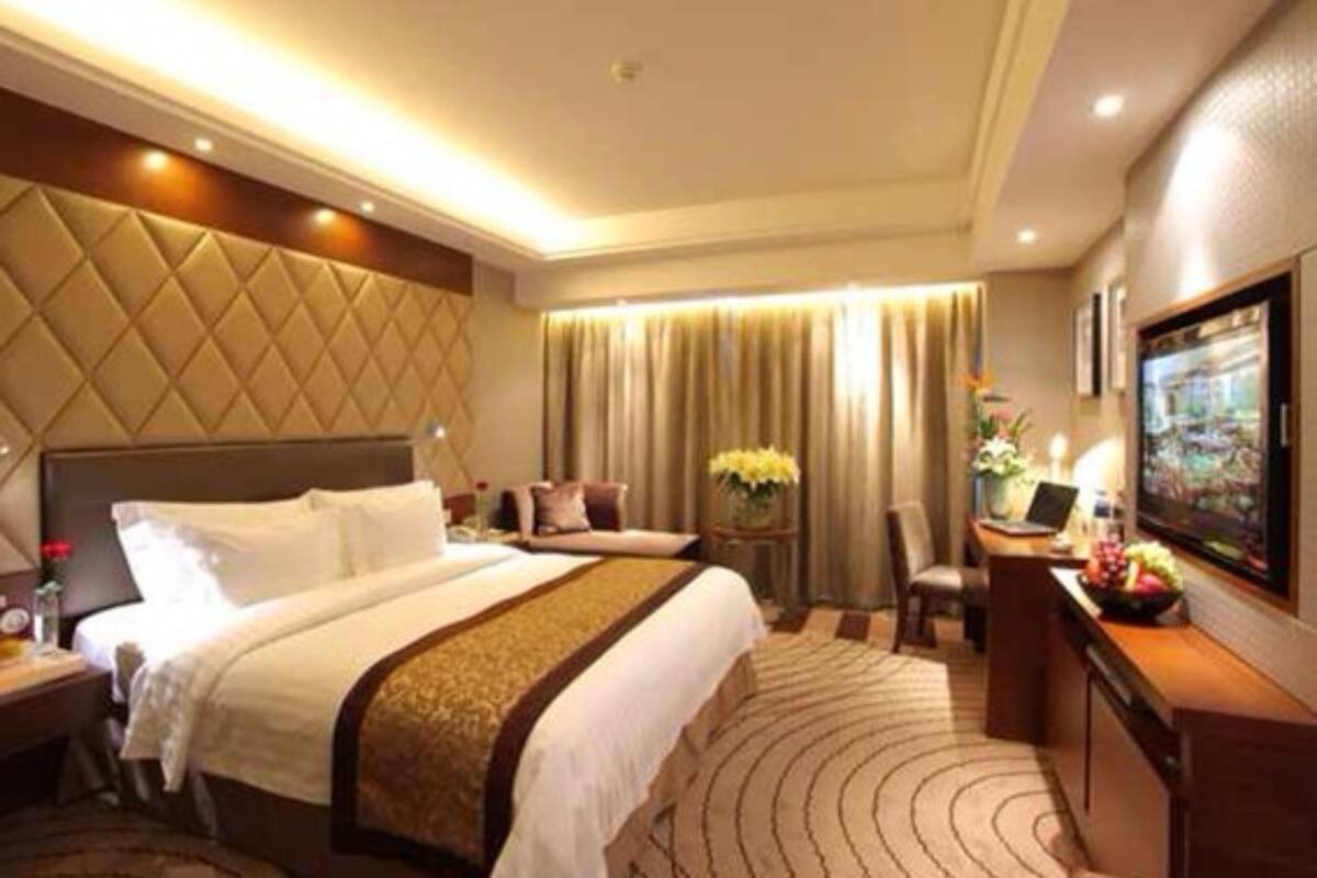 Een hotelkamer met een groot bed, een bureau met een computer, een stoel en een televisie.