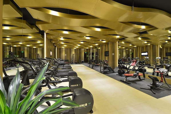 Un gimnasio con cintas de correr, bicicletas estáticas y máquinas de pesas.