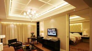 Ein Hotelzimmer mit Fernseher, Bett, Schreibtisch, Stuhl und Teppichboden.