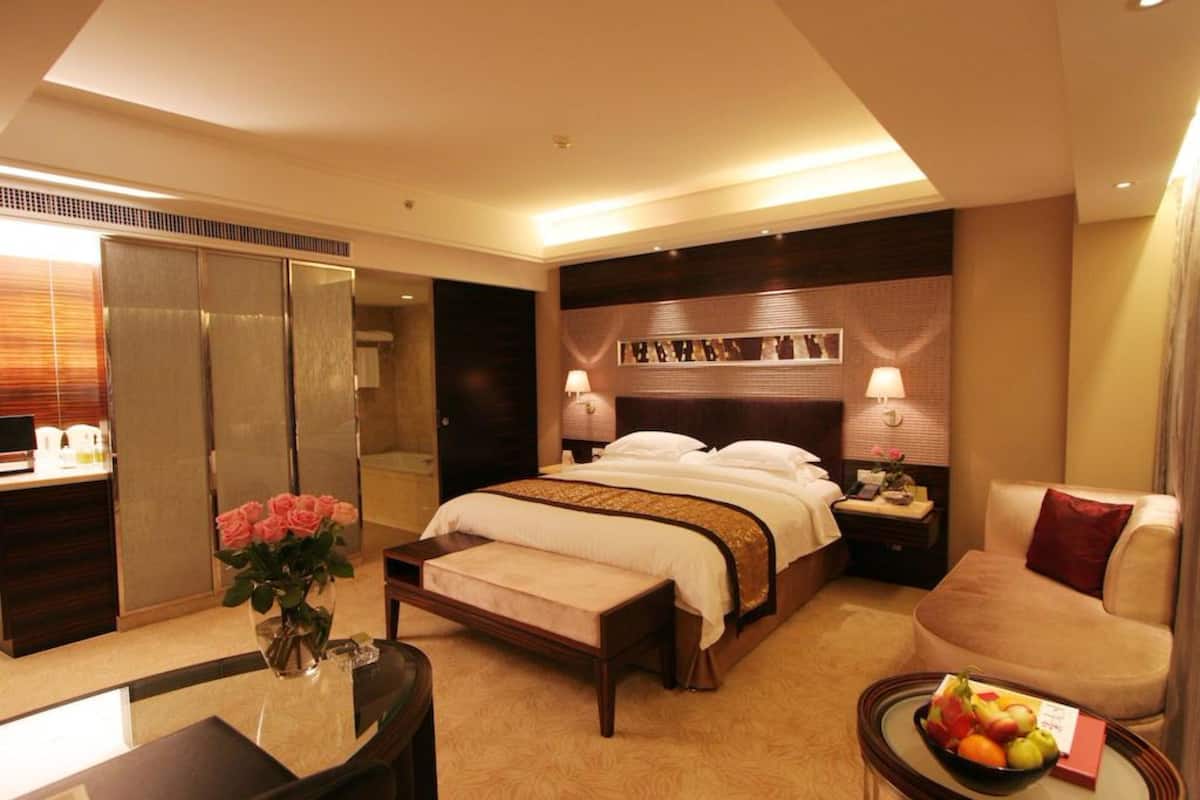 Een hotelkamer met een groot bed, nachtkastjes, een bureau, een stoel en een schaal fruit.