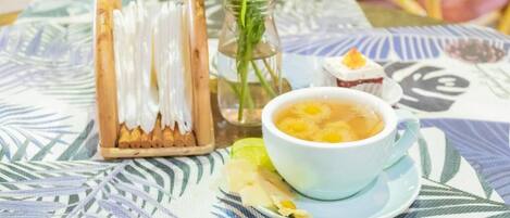 A table with a cup of tea, a small dish with food, and a wooden tray with white items.
