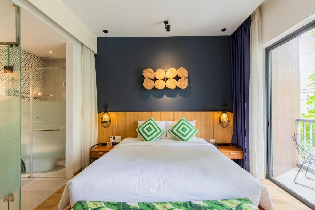 A modern hotel room with a large bed, a geometric wall decoration, and a balcony with a view.