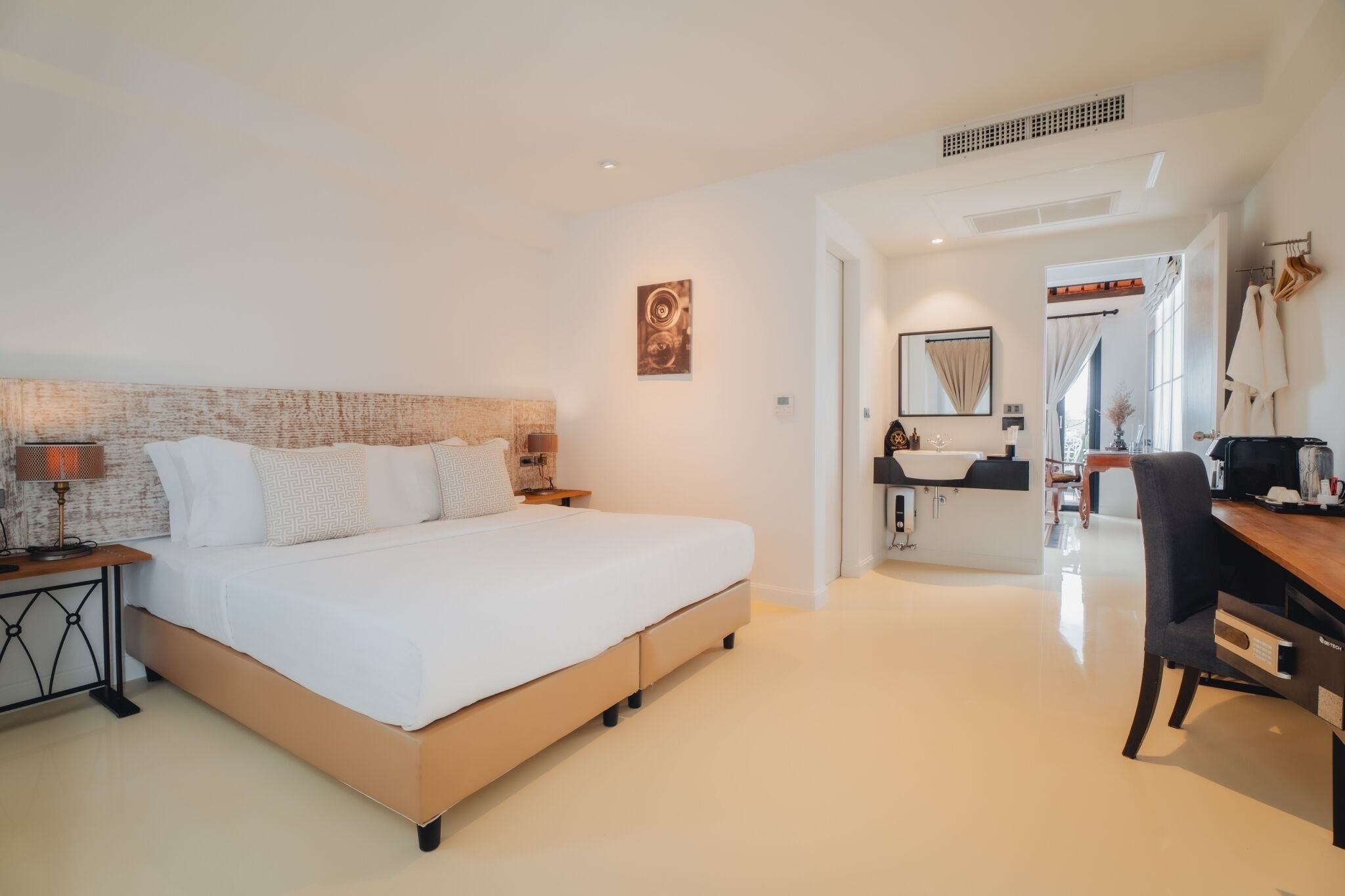 Una habitación de hotel moderna con una cama grande, un escritorio y un baño con lavabo y espejo.