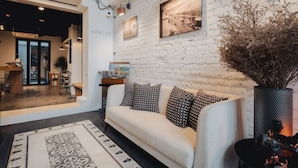A modern interior with a white brick wall, a sofa with patterned cushions, and a decorative vase.
