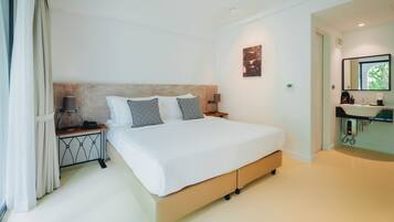 Une chambre d’hôtel moderne dotée d’un grand lit, de lampes de chevet, d’une table de chevet et d’une salle de bain avec un lavabo et un miroir, et offrant une vue sur l’extérieur.