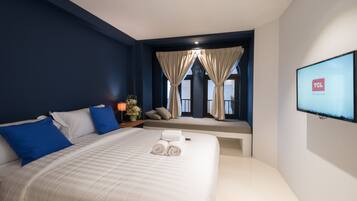 Una habitación de hotel con una cama grande, un televisor en la pared y una ventana con cortinas.
