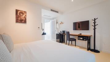 Une chambre d’hôtel moderne équipée d’un grand lit, d’un bureau avec une chaise, d’une télévision et d’un porte-manteau.