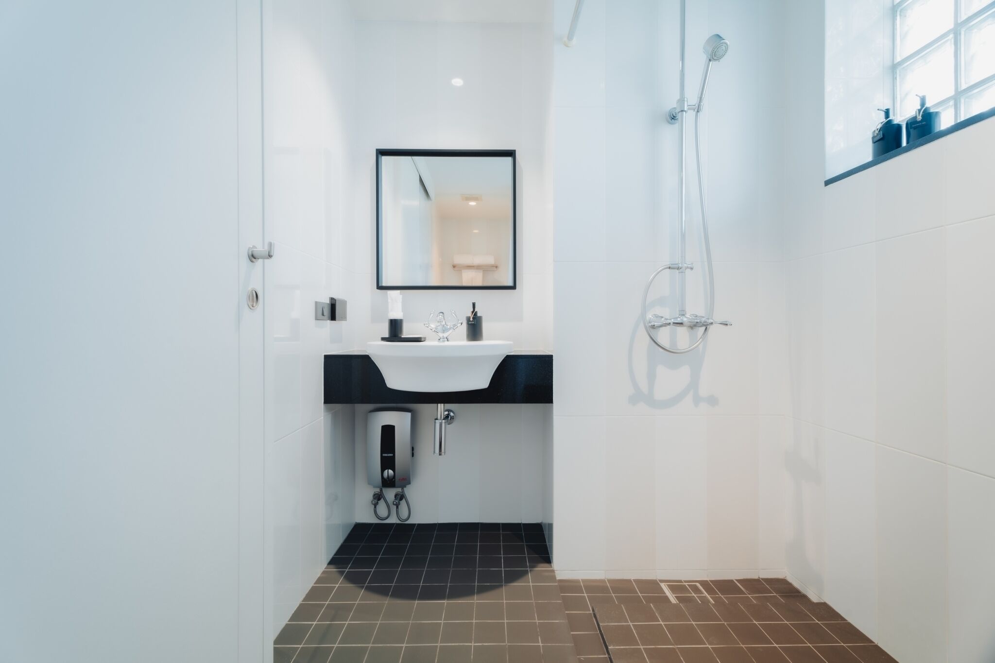 A modern bathroom with a white sink, mirror, and shower.
