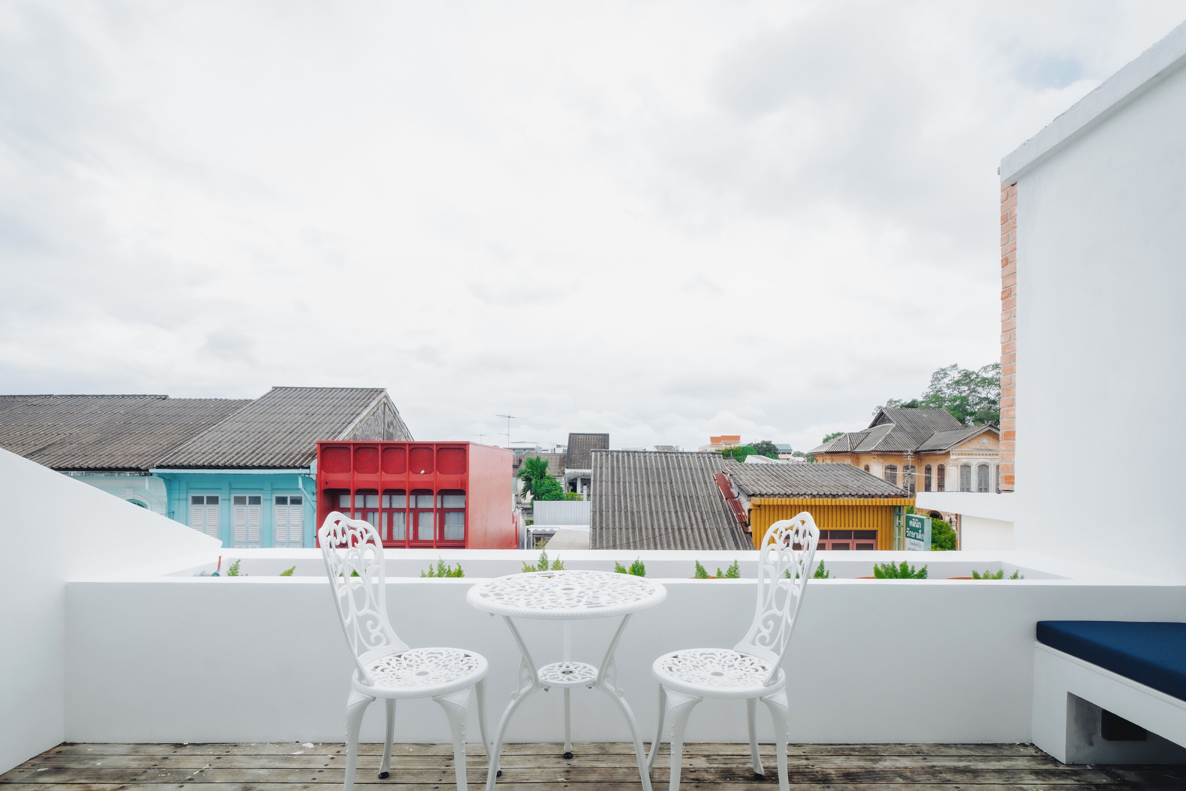 Een balkon met witte stoelen en een kleine tafel, met uitzicht op kleurrijke gebouwen.