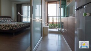 A hotel room with a bed, a sliding glass door leading to a balcony, and a refrigerator. - Baan Thew Lom Cha-Am Huahin by D-light (Cha-am)