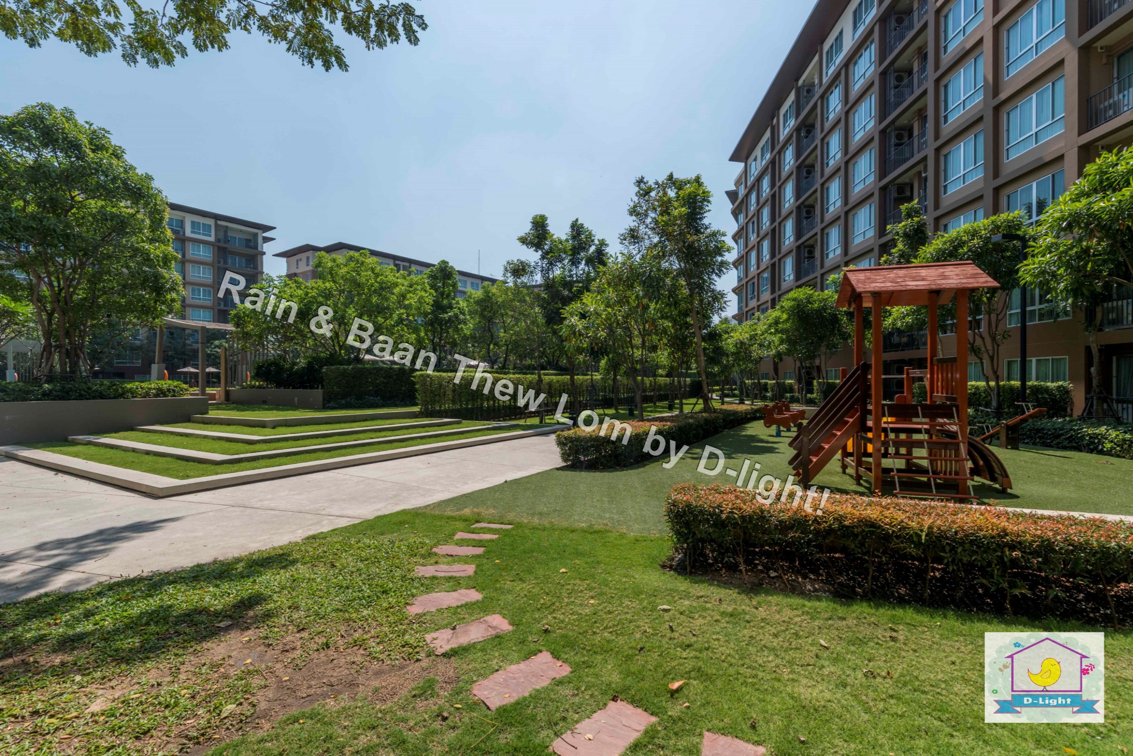 A courtyard with a playground, steps leading to a building, and a well-maintained lawn.