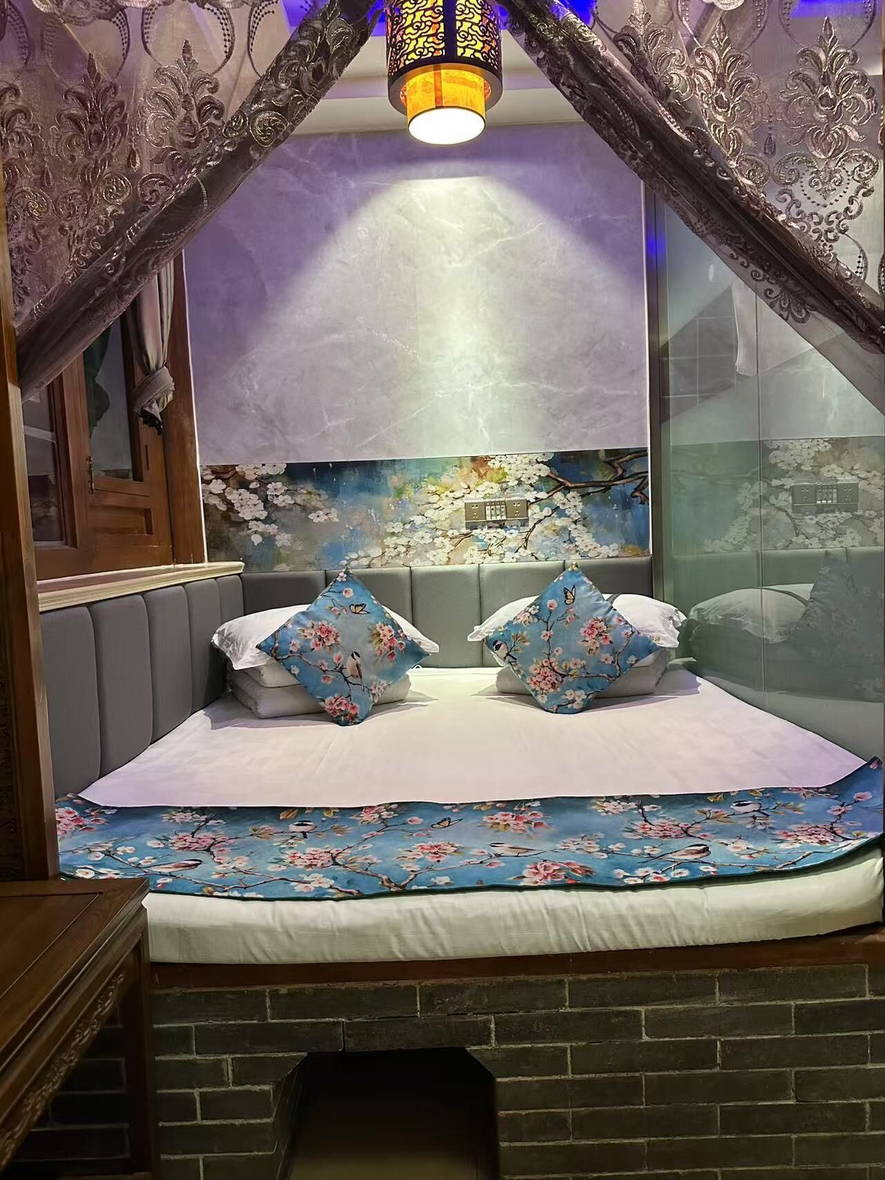 A bedroom with a bed, floral bedding, a decorative canopy, and a mural on the wall.