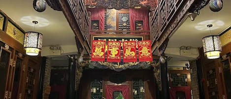 A traditional building with ornate wooden balconies, red lanterns, and a central staircase leading to an upper level.