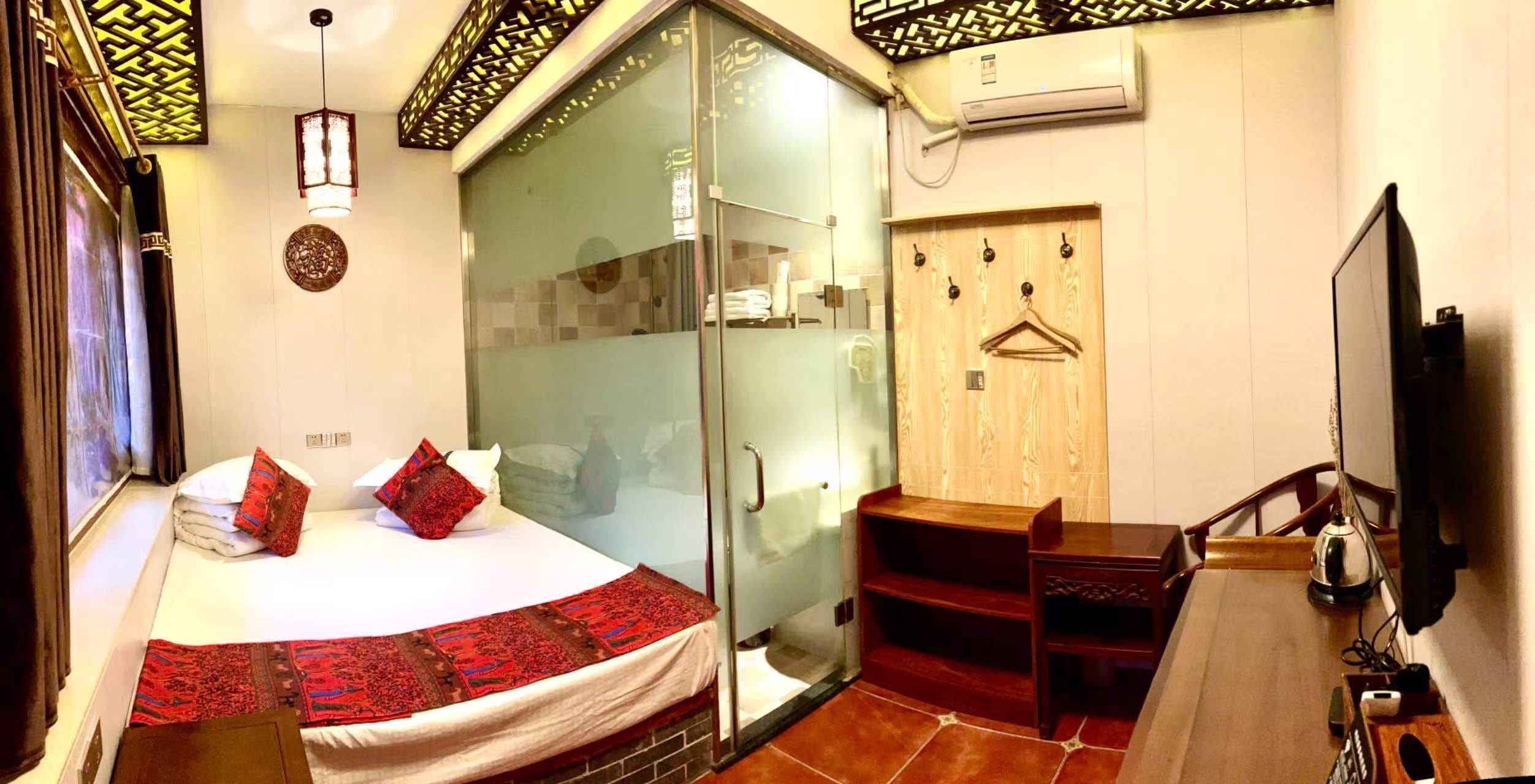 A hotel room with a bed, a desk, a chair, a TV, and a wardrobe.