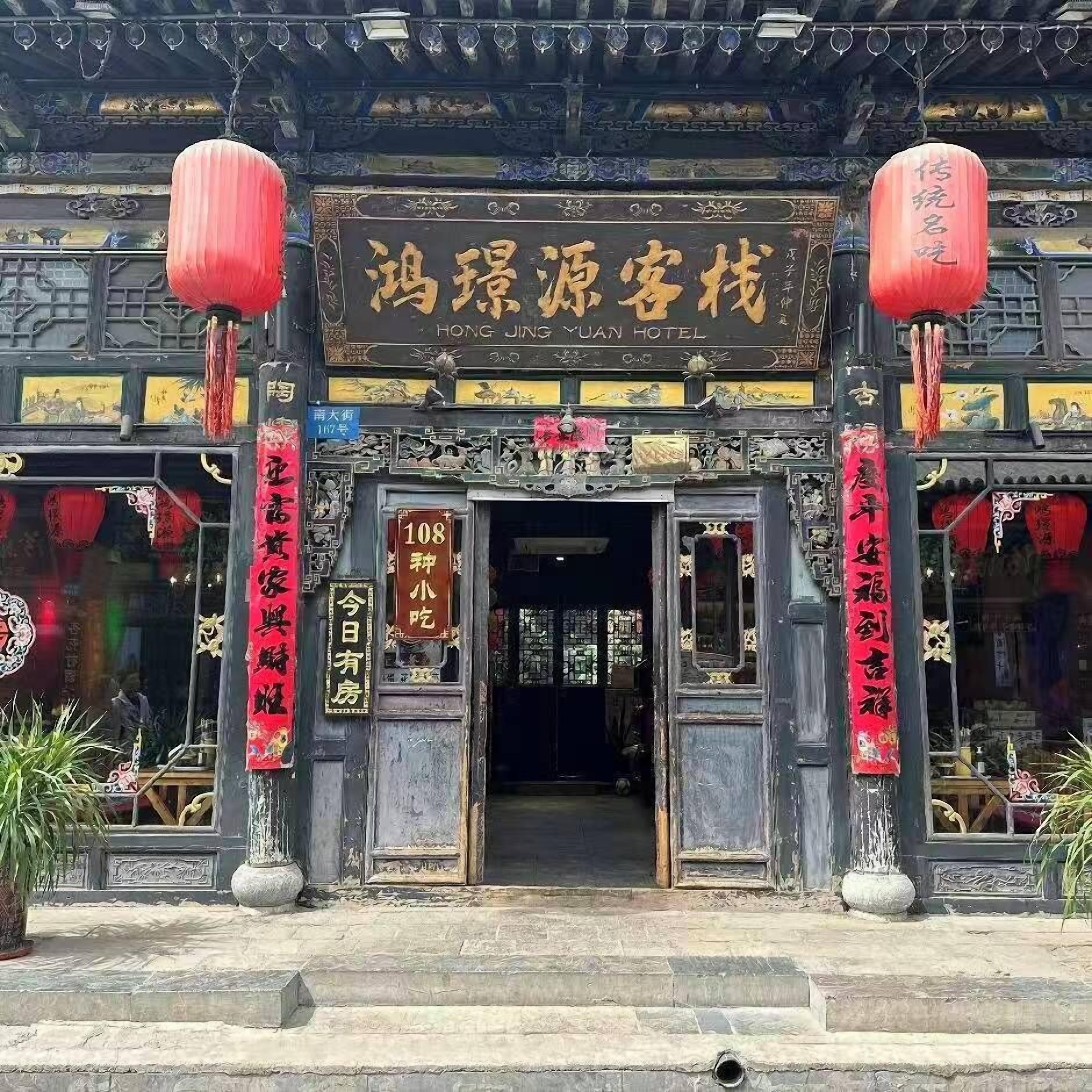 A traditional Chinese building with a sign for 'Hong Jing Yuan Hotel' and a red lantern decoration.