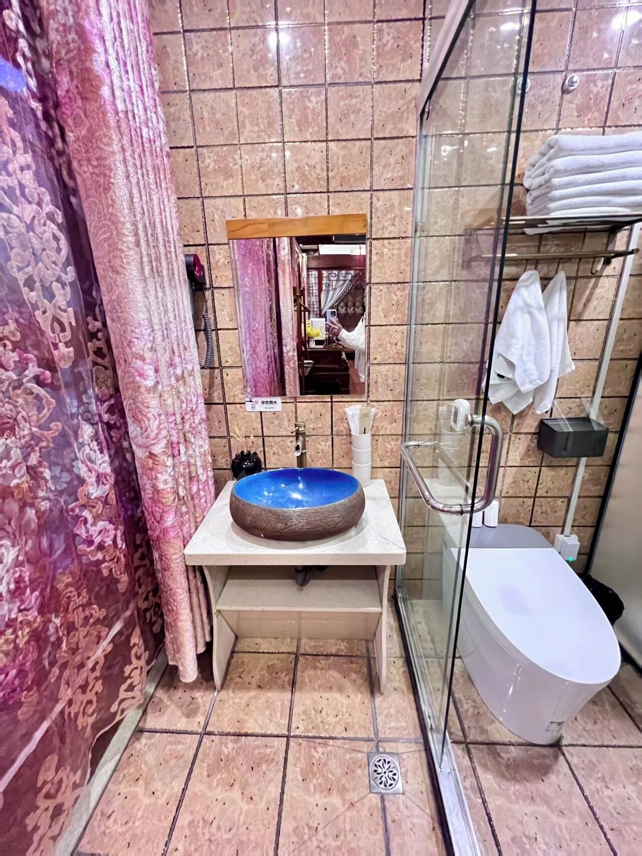 Un baño con un lavamanos azul redondeado, una cabina de ducha de vidrio y un inodoro.
