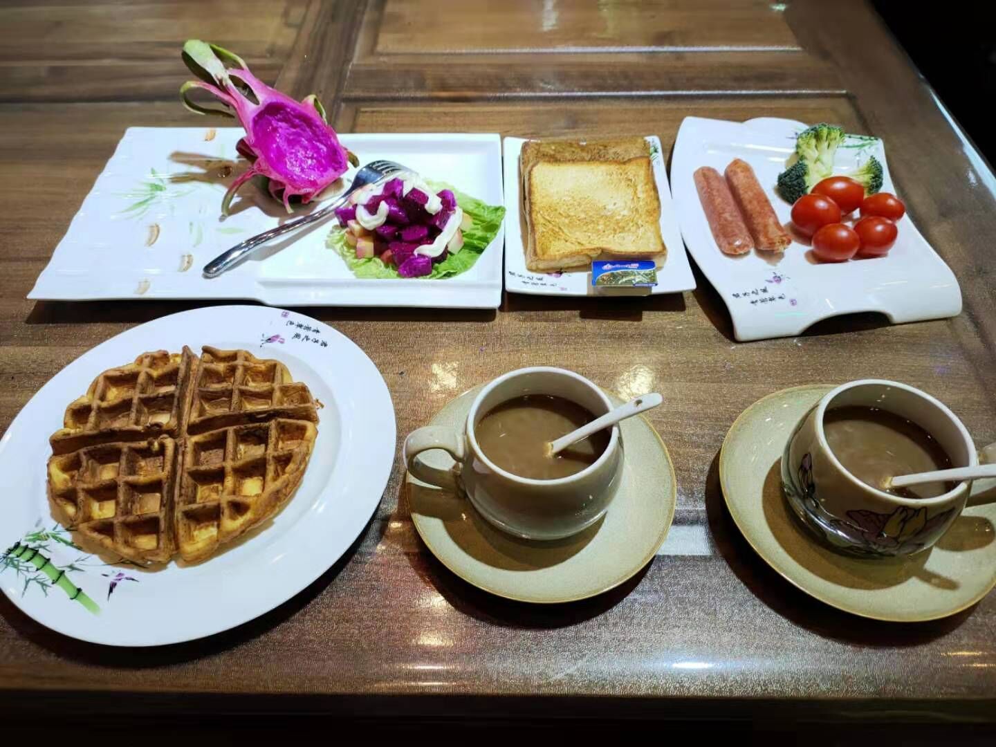 Bandeja de desayuno con waffles, ensalada, tostadas, salchichas y dos tazas de café.