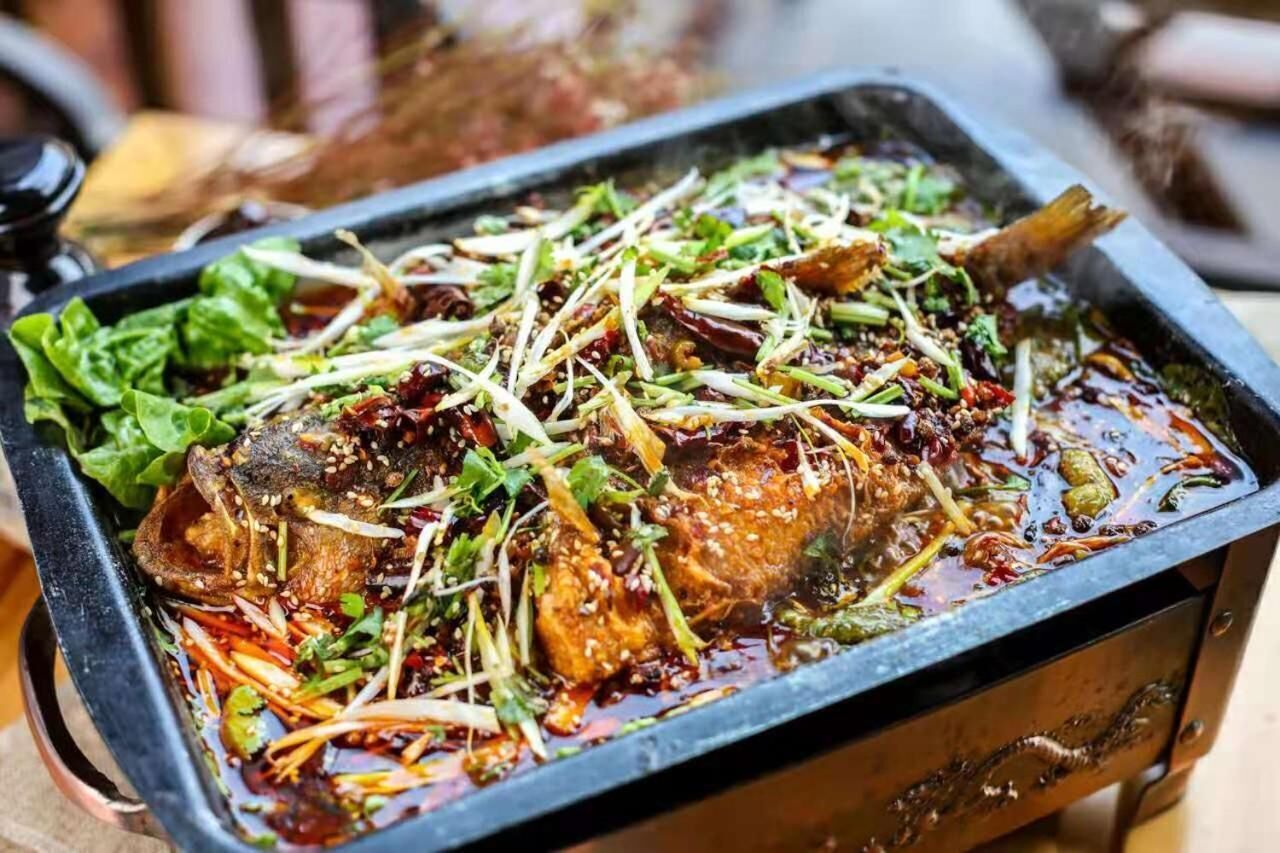 A tray of cooked fish garnished with greens and sesame seeds.