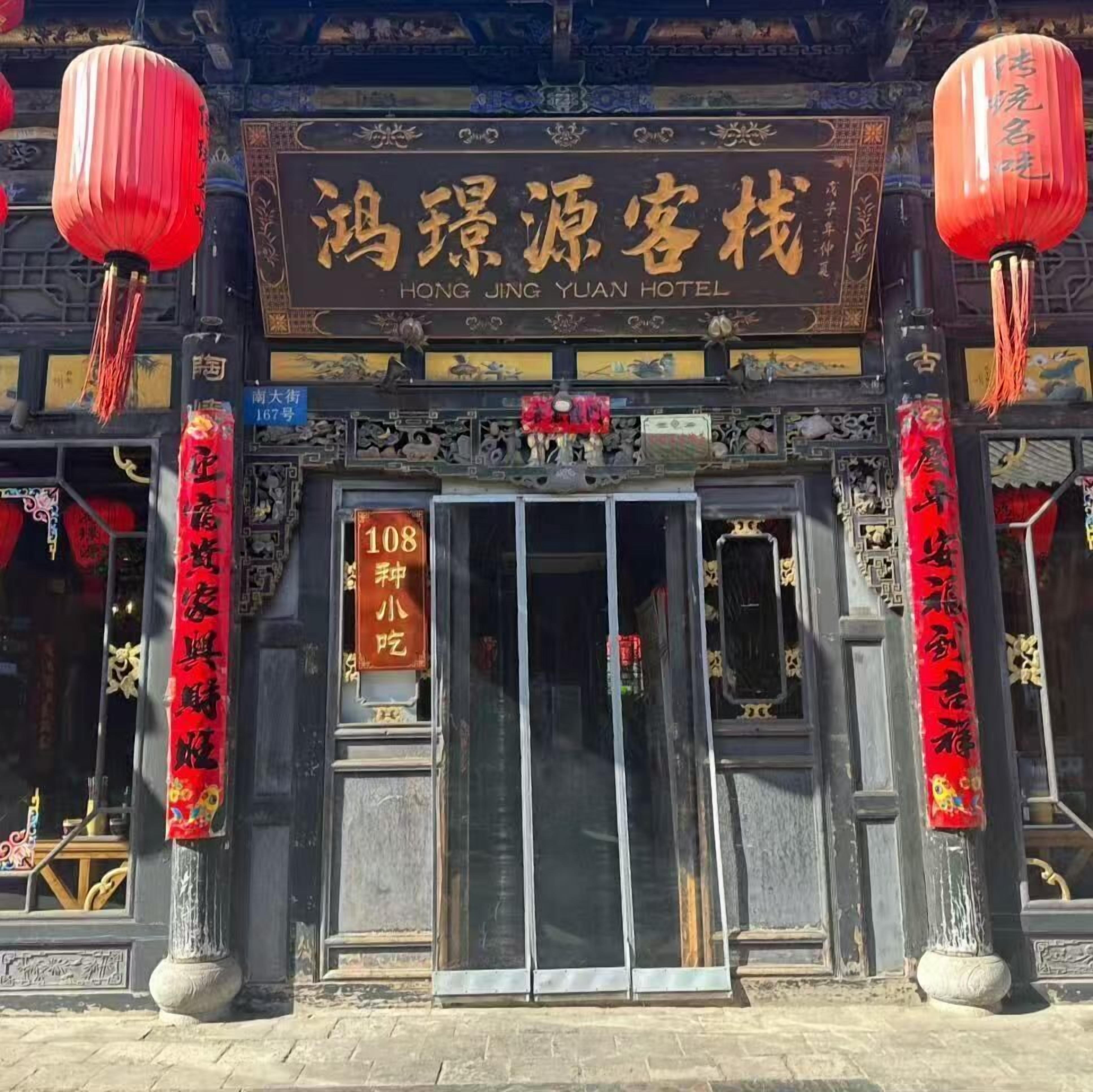 The exterior of Hong Jing Yuan Hotel with traditional Chinese architectural elements, including ornate decorations and red lanterns.