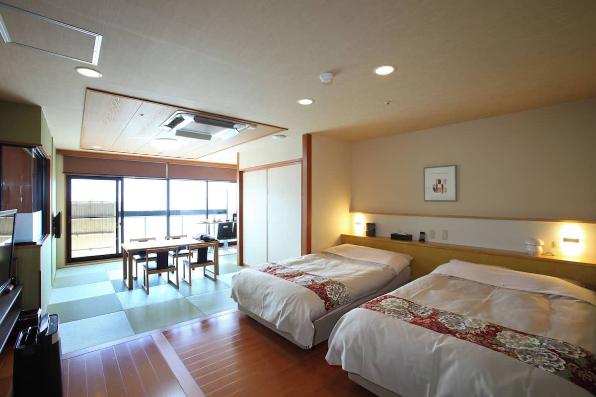 A hotel room with two beds, a desk, and a TV.