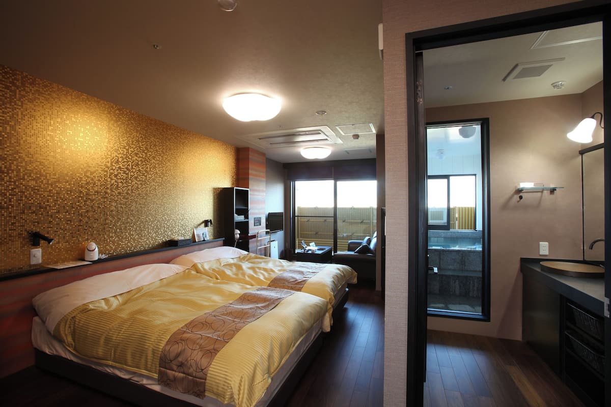 A hotel room with a large bed, a bathroom with a sink, and a view of the outside.