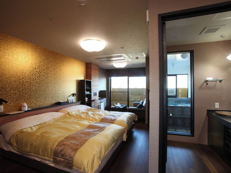 A hotel room with a large bed, a bathroom with a sink, and a view of the outside.