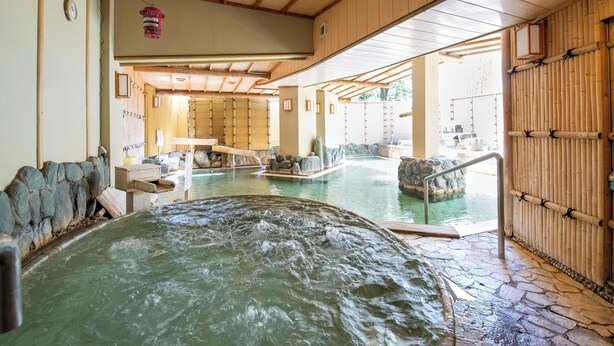 Een traditionele Japanse onsen met stenen vloeren, houten balken en een warmwaterbron op de voorgrond.