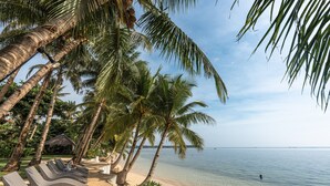A beach with lounge chairs and palm trees. - Siargao Island Villas (General Luna)