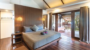 A spacious bedroom with a large bed, wooden headboard, and a view of an outdoor deck. - Siargao Island Villas (General Luna)