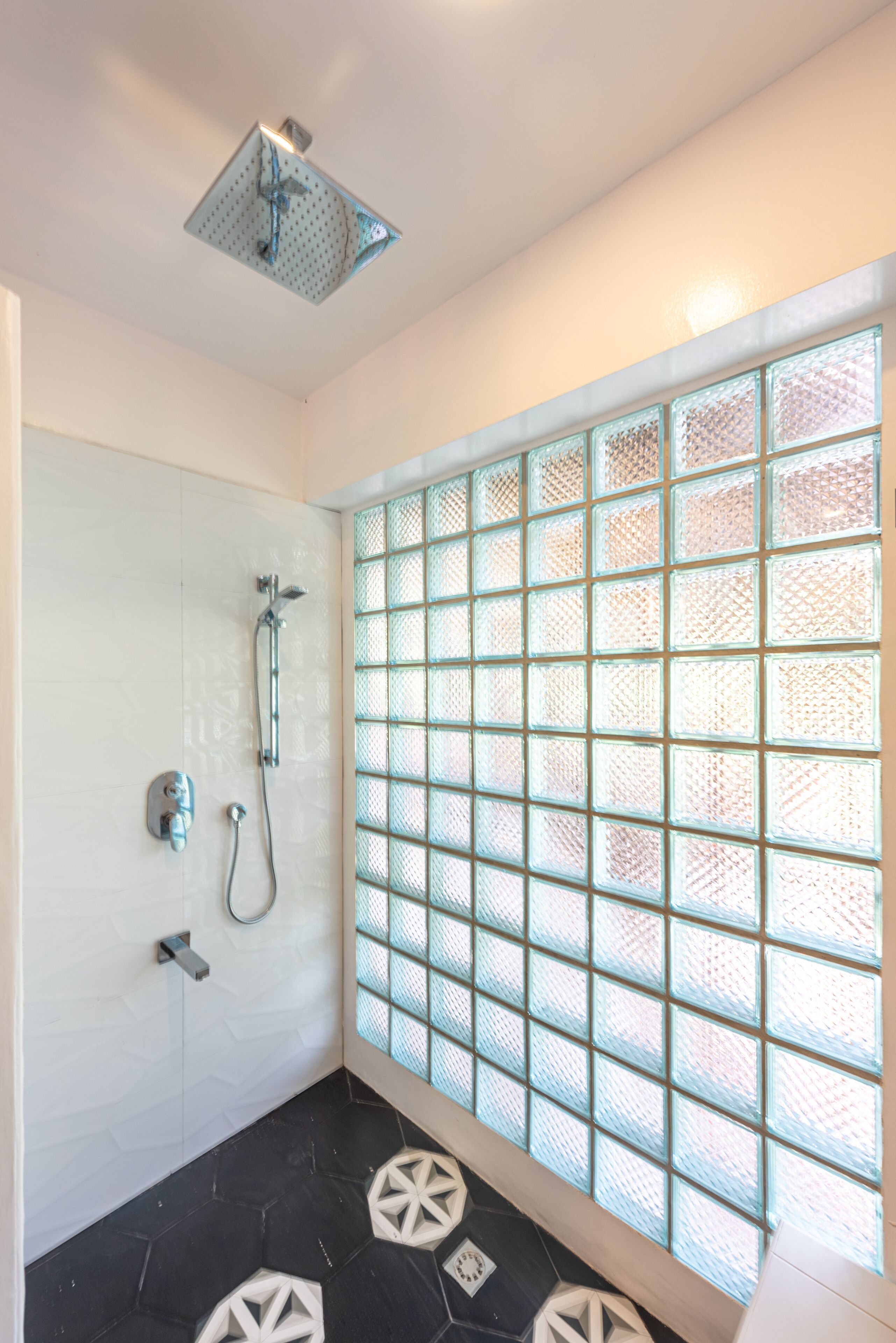 A bathroom with a shower, a glass block wall, and a tiled floor.