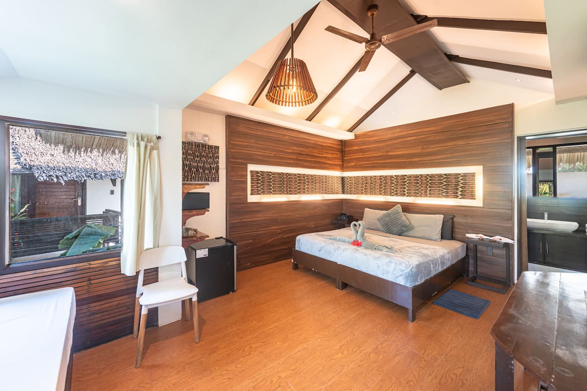 Ein modernes Schlafzimmer mit Bett, Schreibtisch, Stuhl, Deckenventilator und Blick ins Freie.