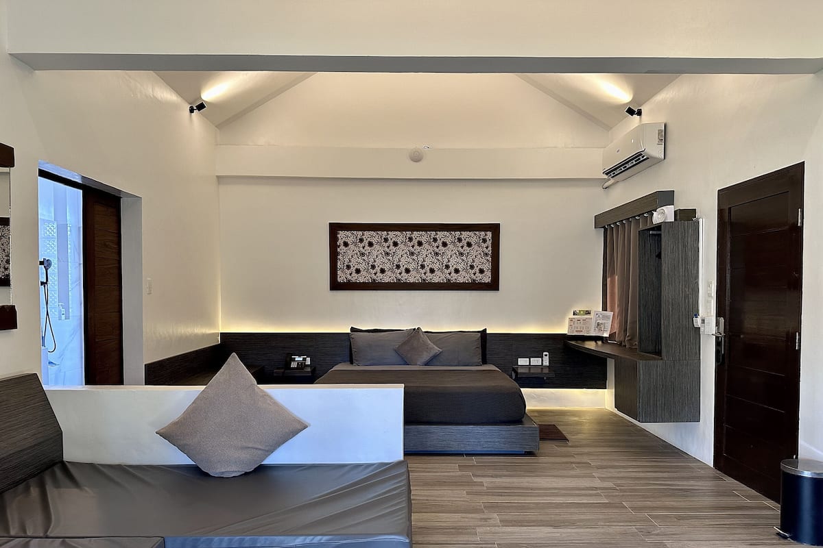 Ein modernes Hotelzimmer mit einem großen Bett, einer Couch, einem kleinen Tisch und einem großen Fenster.