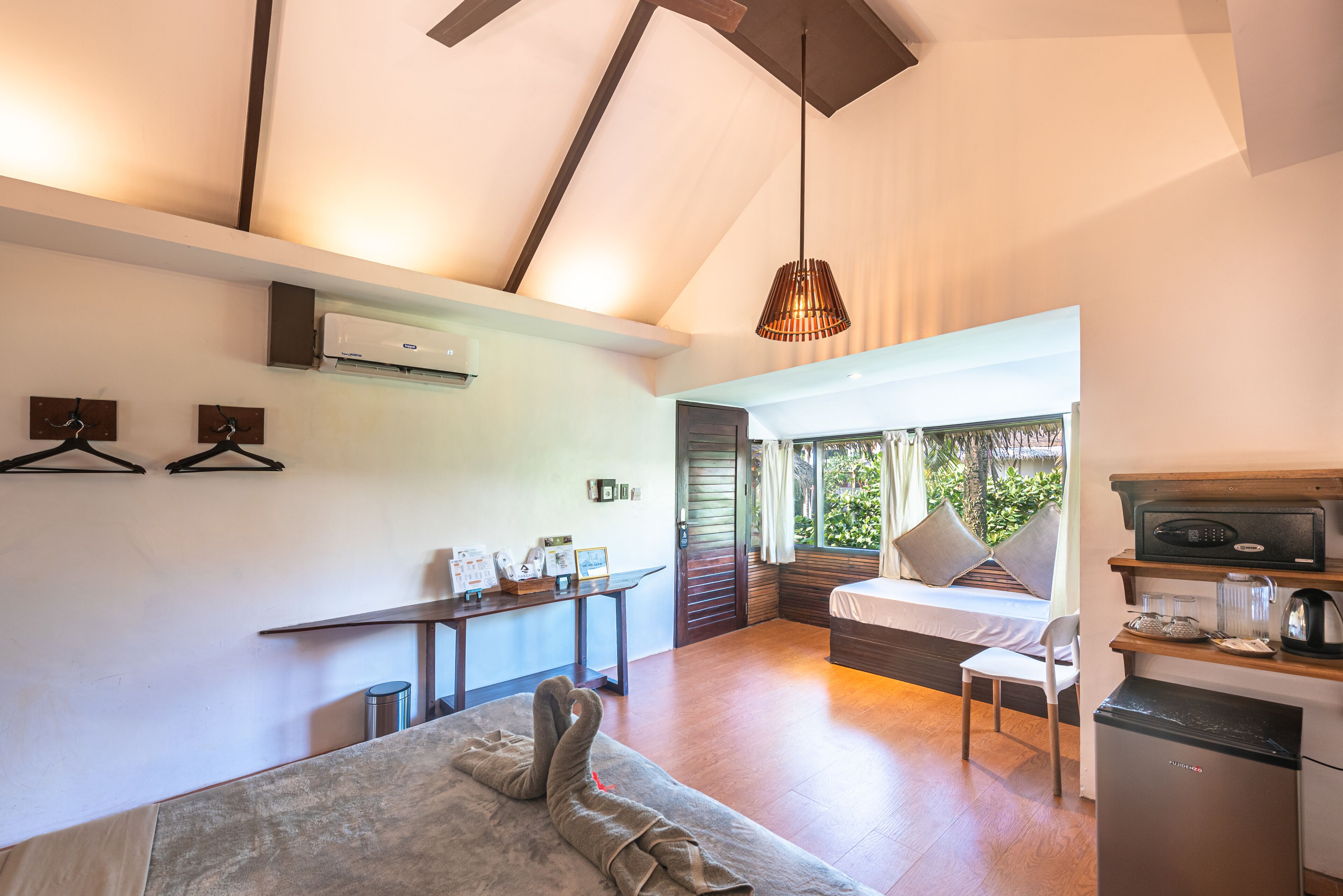 A modern bedroom with a bed, a desk, and a kitchenette.