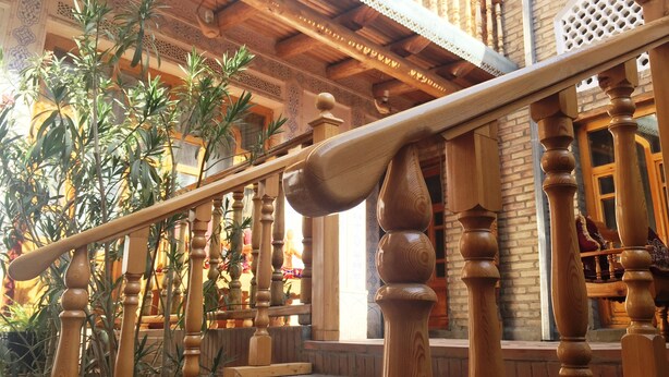 Een houten trap met gedetailleerde balustrades en een balustrade, die leidt naar een balkon met betegelde vloeren.