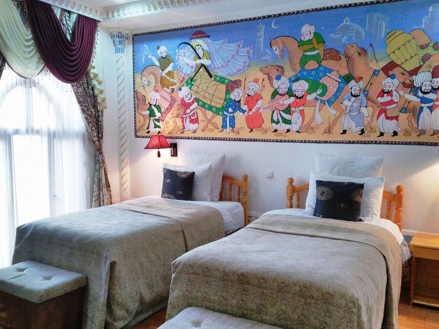 Ein Zimmer mit zwei Betten, einer großen Wandmalerei und einem Fenster mit Vorhängen.