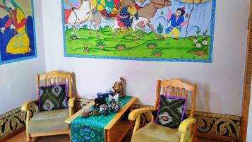 Traditional room with two chairs, a small table, and decorative artwork adorns the walls.