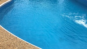 A clear blue swimming pool with a pebble-lined edge and a curved design. - Valley View Motel (Murrurundi)