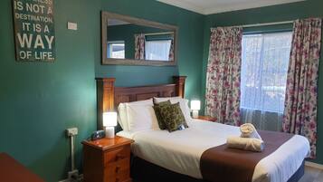 A neatly made bed with a brown blanket, two bedside lamps, and a floral curtain.