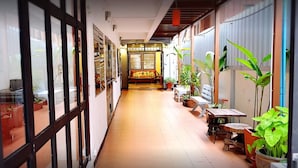 Un pasillo estrecho con un banco de madera, plantas en macetas y piso de baldosas.