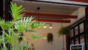 Un restaurante con una estatua de león de piedra, una planta grande en maceta y un cartel que anuncia habitaciones disponibles.